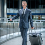 Full-size portrait of a joyful confident determined entrepreneur trundling his trolley suitcase by the telescopic metal handle